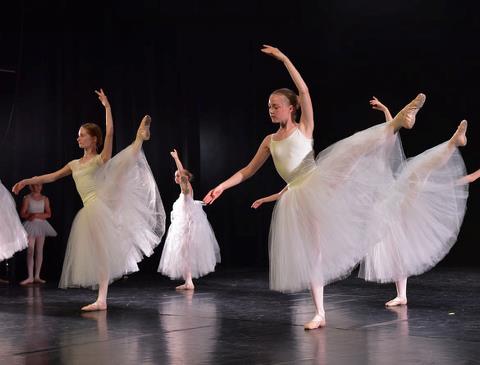 Billedet viser balletpiger Avanceret B der træner i balletsalen i hvide kostumer. 
